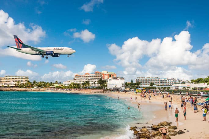 Delta flight approaches St Maarten's Princess Juliana Airport above onlookers on Maho Beach